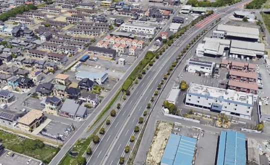 上空から見た、多くの住宅が立ち並ぶ幹線道路と町並みの様子